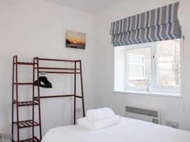 A bedroom with a bed and hanging rack at Gilly's Cottage in Hope Cove