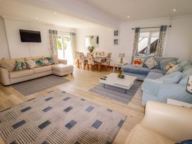 A living room with a sofa, coffee table, and dining area at Charlecote House in Saundersfoot