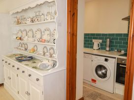 A kitchen with a shelf displaying dishes and appliances at Charlecote House in Saundersfoot