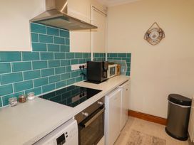 A kitchen with appliances and teal tiles at Charlecote House in Saundersfoot