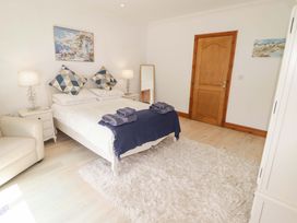 A bedroom with a bed and armchair at Charlecote House in Saundersfoot