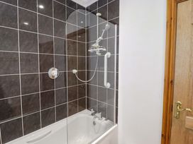A bathtub with a shower enclosure in Charlecote House Saundersfoot