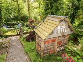 A bug hotel in a garden with chairs and plants at Charlecote House in Saundersfoot
