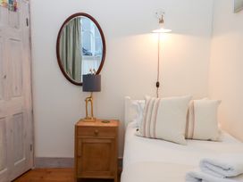 A bedroom with a bed, nightstand, lamp, and mirror at 13 Above Town in Dartmouth