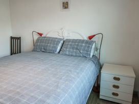 A bedroom with a bed, nightstand, and lamp at 7 Bro Branwen Aberffraw near Rhosneigr