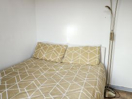 A bed with patterned bedding and a floor lamp at 7 Bro Branwen Aberffraw near Rhosneigr