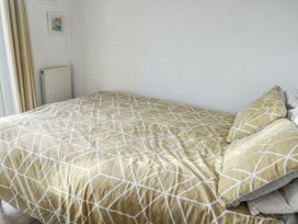 A bedroom with a bed covered in patterned bedding at 7 Bro Branwen Aberffraw near Rhosneigr