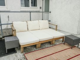 A sofa with cushions and a side table on a patio area at 7 Bro Branwen Aberffraw near Rhosneigr