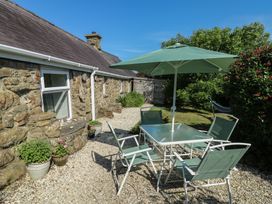 A garden with a table and chairs under a parasol at Sunstone (Garreg Haul) Cilan near Abersoch