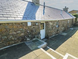 An outdoor area with a stone wall and door at Sunstone (Garreg Haul) Cilan near Abersoch