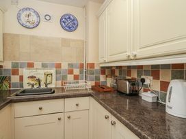 A kitchen with a sink, toaster, kettle, and decorative tiles at Dollar Ward House Basement Cirencester