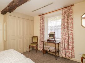 A bedroom with a wardrobe, chair, table, and mirror at Dollar Ward House Basement Cirencester