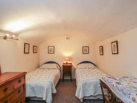 A bedroom with two beds and a bedside table at Dollar Ward House Basement in Cirencester