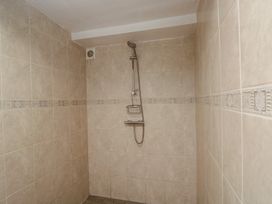 A bathroom with a shower and tiled walls at Dollar Ward House Basement Cirencester