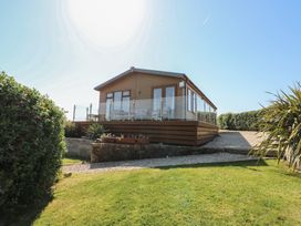A lodge with glass railing and plants at Sunstone Lodge (Garreg Haul Lodge) Cilan near Abersoch
