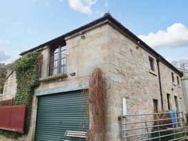 An outdoor view of a stone building with a balcony and garage at The Granary in Rothbury