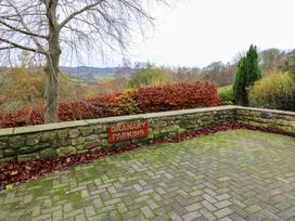 An outdoor parking area with a stone wall and sign at The Granary in Rothbury