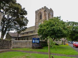 A church with clock tower and bench outside at The Granary in Rothbury