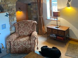A living room with an armchair and a table lamp at Swaledale Watch Garden Annexe in Caldbeck