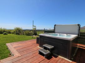 A hot tub with steps on a wooden deck at Cefnbron in Llanaelhaearn near Trefor