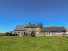 An exterior view of a stone house with a grass area at Cefnbron Llanaelhaearn near Trefor