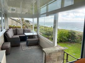 A conservatory with seating and a table overlooking the sea at Stonecroft in Praa Sands