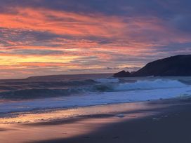 A beach at sunset with waves and hills at Stonecroft in Praa Sands