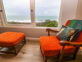 A snug area with an armchair and ottoman overlooking the ocean at Stonecroft in Praa Sands