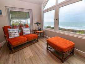 A living room with a sofa, telescope and large windows at Stonecroft in Praa Sands
