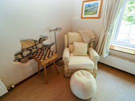 A snug with an armchair and chess table at The Stables in St Athan