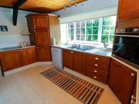 A kitchen with wooden cabinets and sink at The Stables in St Athan