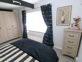 A bedroom with a bed, wardrobe, curtains, and window at The Stables in St Athan