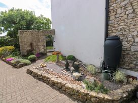 A garden with a stone wall and flower beds at The Stables in St Athan