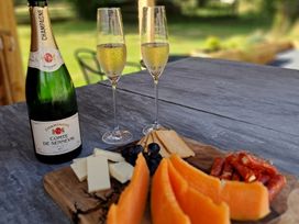 An outdoor dining area with champagne and a cheese platter at Carreg Cennen Cottage, Llandeilo