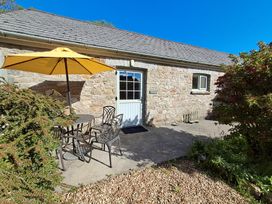 An outdoor area with a table and chairs under an umbrella at Carreg Cennen Cottage Llandeilo