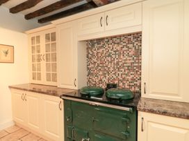 A kitchen with a green stove and mosaic backsplash at Butlers Cottage in Burford