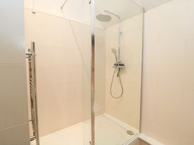 A shower with glass door and chrome fixtures at Butlers Cottage Burford