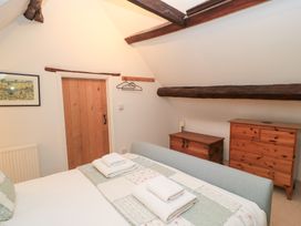 A bedroom with a bed and wooden furniture at Butlers Cottage in Burford