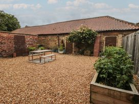 A garden with gravel, a table, and planters at Black Horse Cottage in Swainby