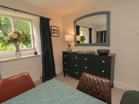 A dining room with a table and flowers on the dresser at Black Horse Cottage in Swainby