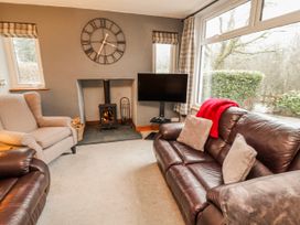 A living room with a fireplace and television at Greenbank Cottage Winster near Bowness-On-Windermere