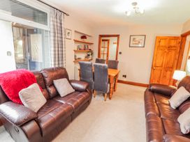 A living room with a sofa and dining table at Greenbank Cottage in Winster near Bowness-On-Windermere