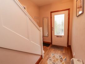 A hallway with a staircase and front door at Greenbank Cottage in Winster near Bowness-On-Windermere
