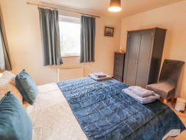 A bedroom with a bed and wardrobe at Greenbank Cottage in Winster near Bowness-On-Windermere