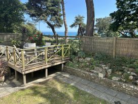 A garden with a deck, table, and chairs overlooking the sea at Hoppapill House in Bournemouth