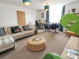 A living room with a sofa, coffee table, and dining area at Beachcomb in Weymouth