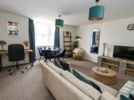 A living room with a sofa, coffee table, and dining area at Beachcomb in Weymouth
