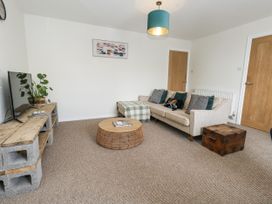 A living room with a sofa, coffee table, and television at Beachcomb in Weymouth
