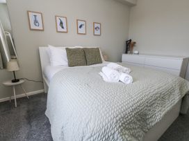 A bedroom with a bed, towels, and wall art at Beachcomb in Weymouth