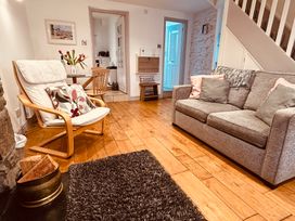 A living room with a gray sofa and armchair and a dining area visible at 7 Watkin Street in Conwy